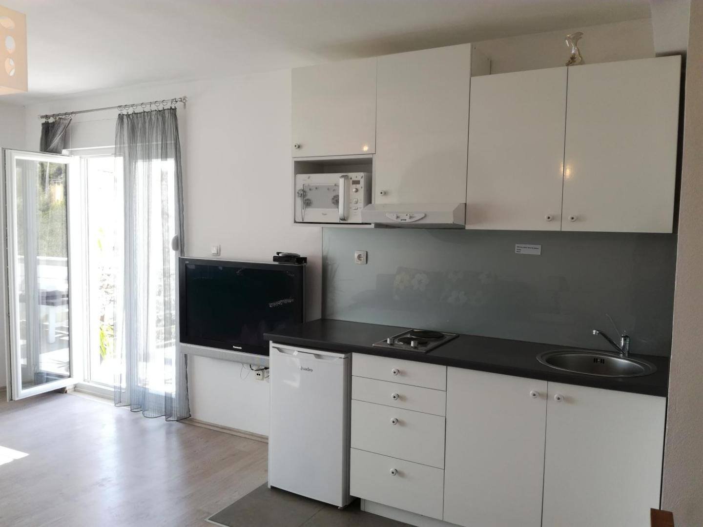 Guest House Dragić: kitchen with white cabinets and a dark countertop