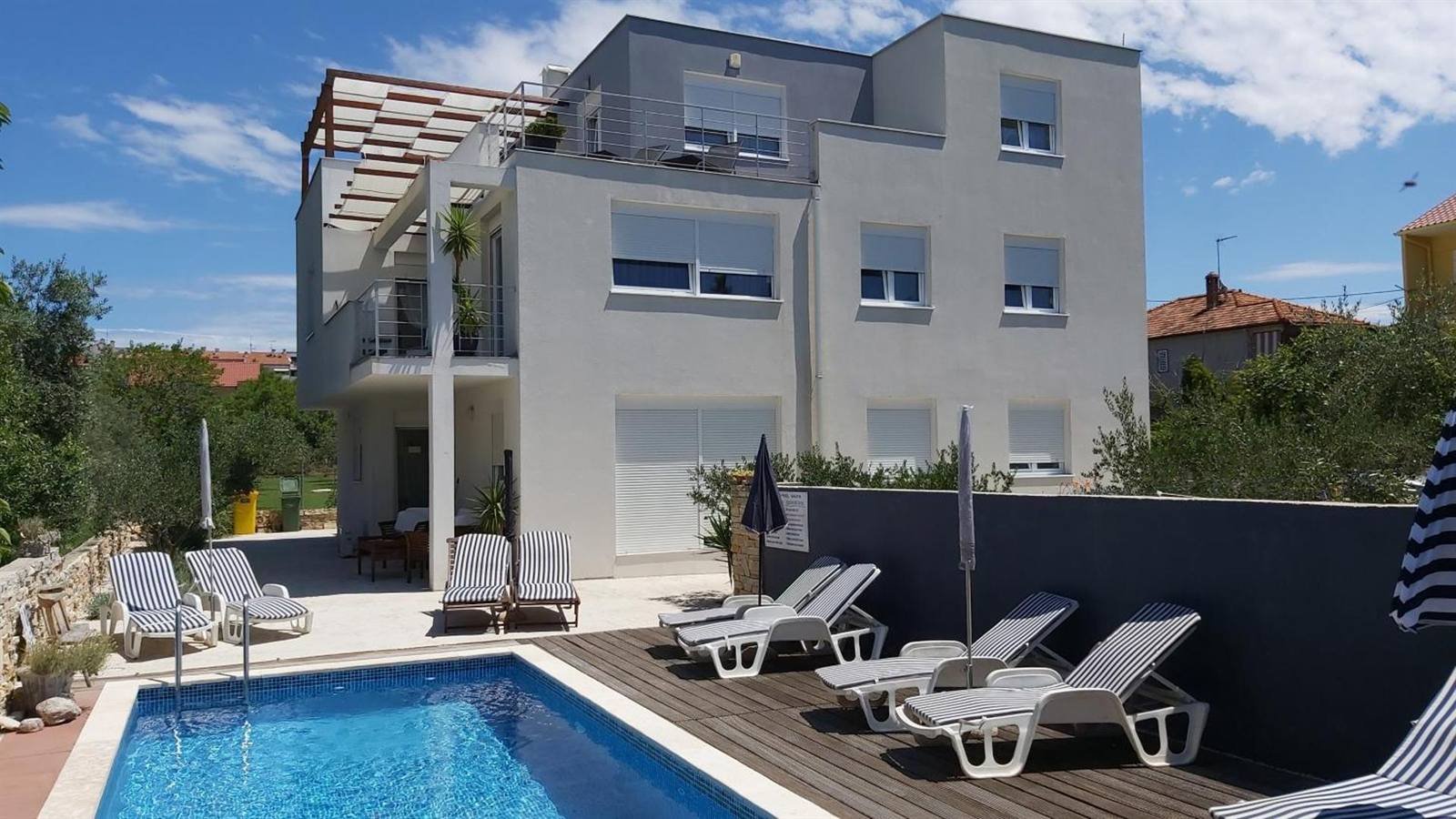 Guest House Dragić: pool, garden chairs and the building